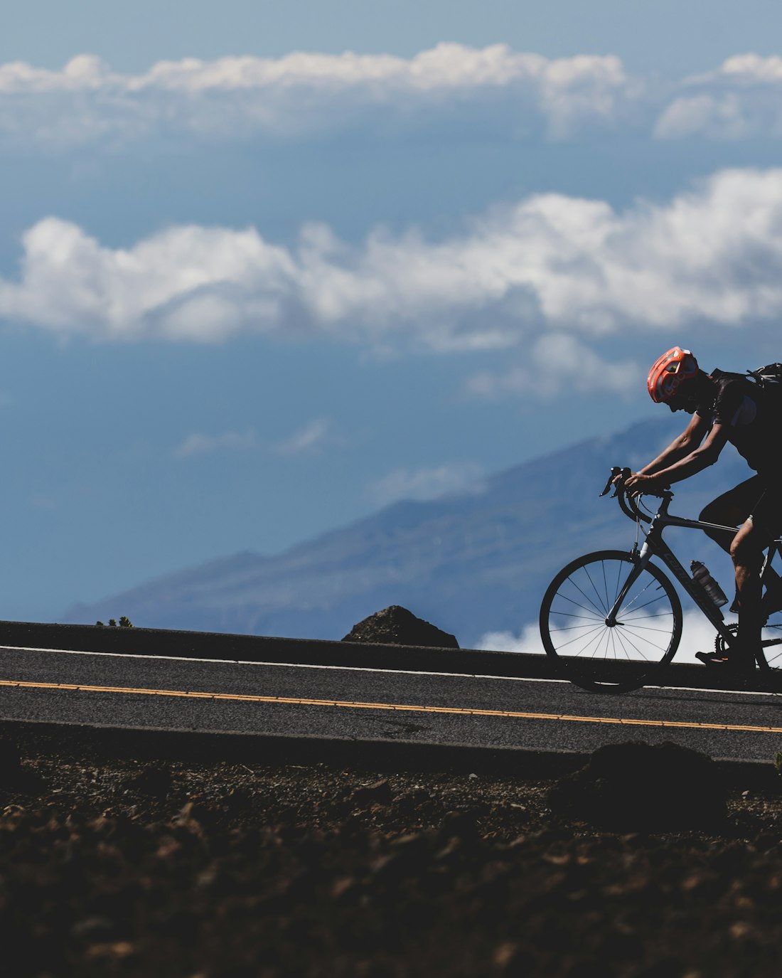A road cyclist climbing a mountain road high above the clouds